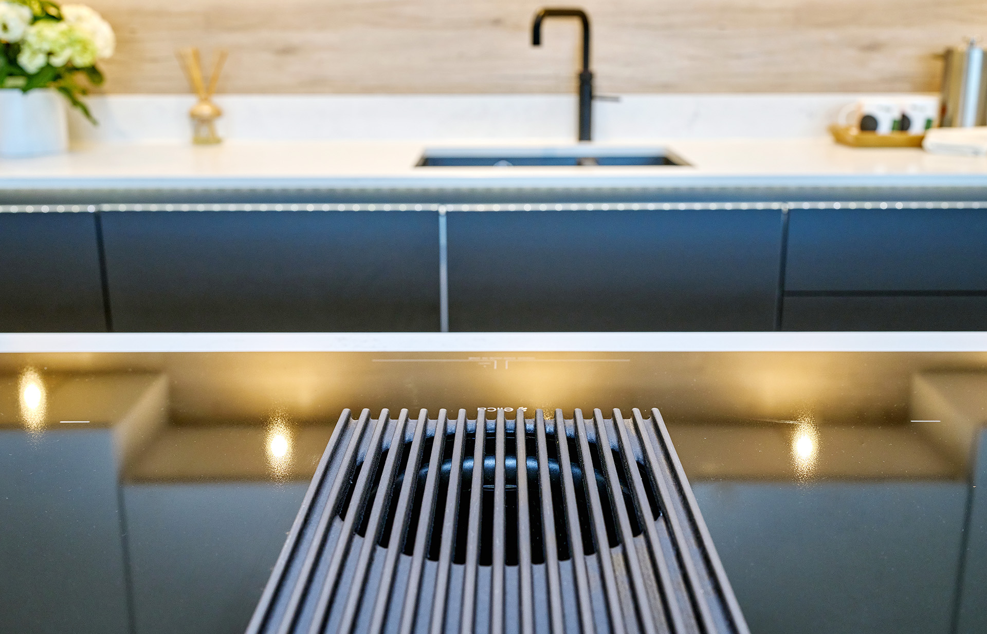 Modern kitchen with extractor fan built into the hob on the kitchen island opposite the Quooker tap