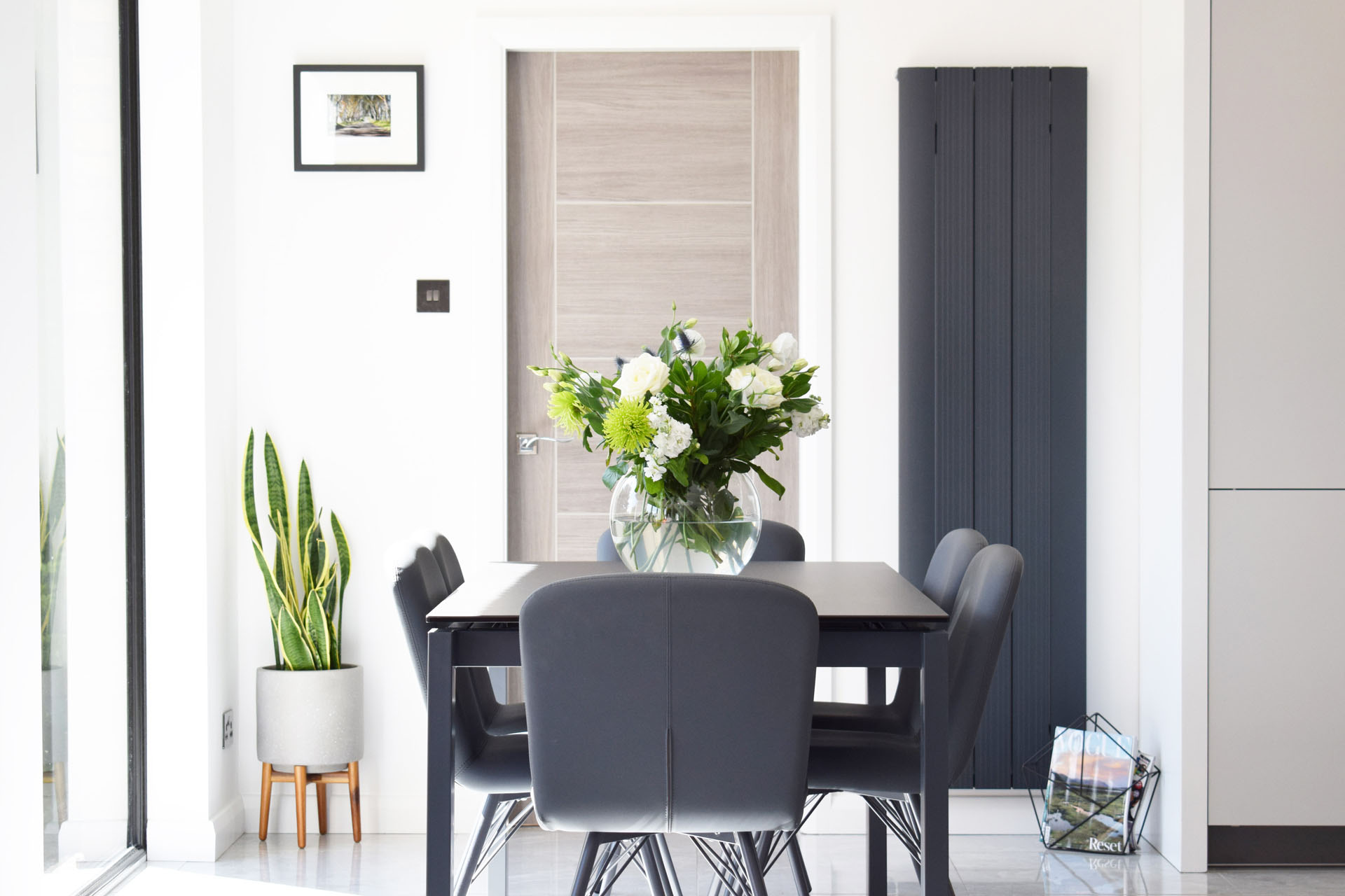 Modern kitchen with clean and luxury design. Plenty of natural light coming through onto the dining room table and chairs
